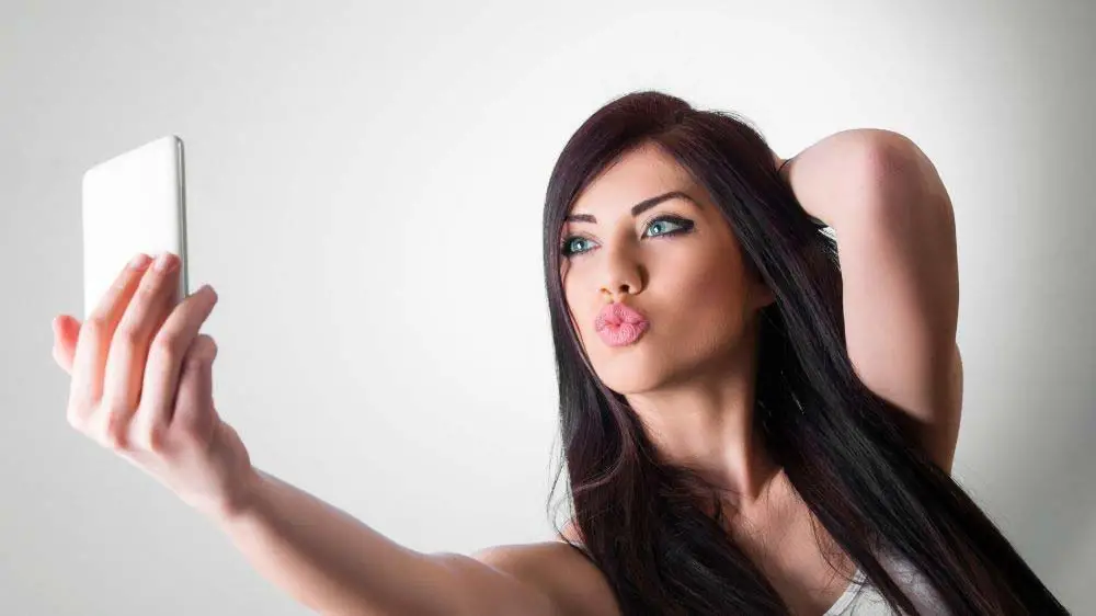 Woman creating a duck lips selfie.