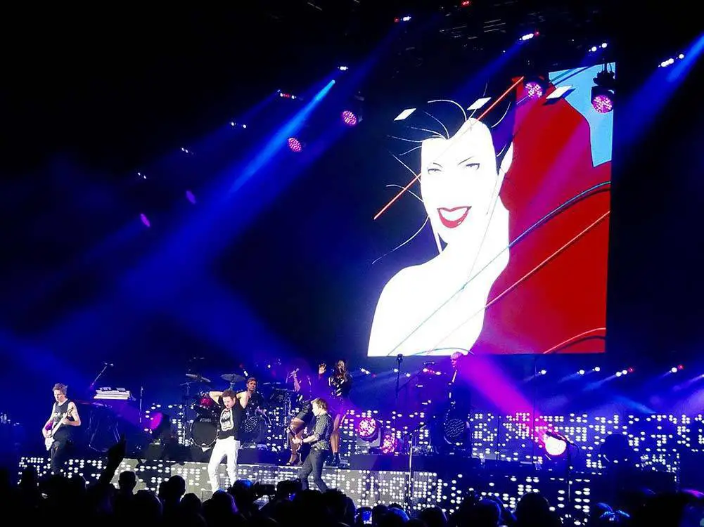 The famous Patrick Nagel image from the album Rio displayed on stage behind the band.