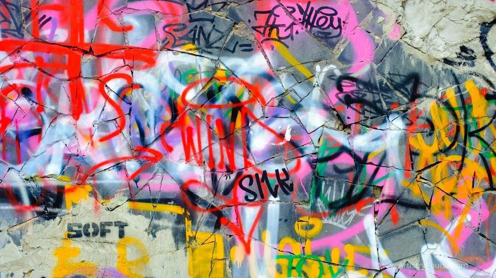 Graffiti tags painted over one another on a wall.